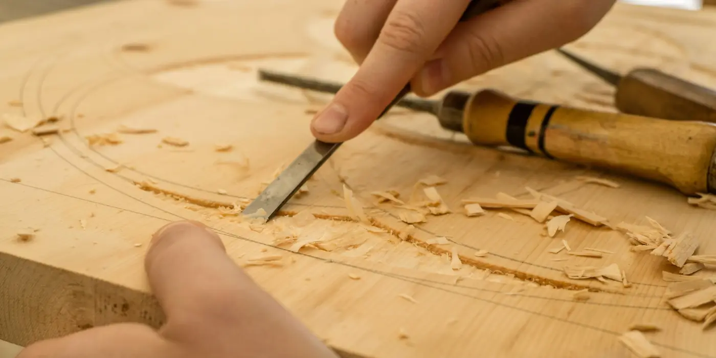 Close-up of hands using a chisel to carve wood