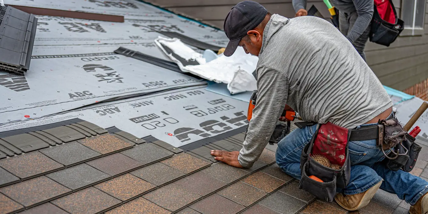 Roofer installing asphalt shingles on a house